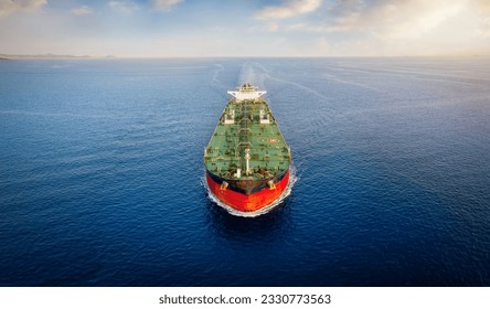 Aerial front view of a heavy crude oil tanker traveling over calm sea during sunset
