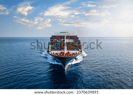 Aerial front view of a large, loaded container cargo vessel traveling over calm ocean