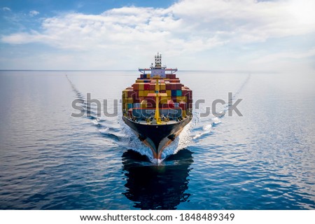 Aerial front view of a loaded container cargo vessel traveling over calm ocean