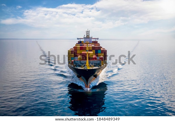 Aerial front view of a loaded container cargo\
vessel traveling over calm\
ocean