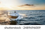 Aerial front view of a motor boat cruising with speed over the ocean during sunset time with copy space