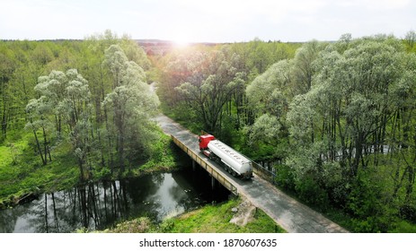 Aerial. The Fuel Gasoline Truck Is Crossing The Little Rural Bridge. Beautiful Nature Around. View Above From Drone. 