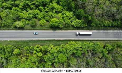 Aerial. Gasoline fuel truck driving by the highway road between green forest. Top view.