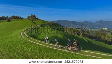 AERIAL: Group of young cyclists pedalling along a mountain trail, framed by stunning scenic views and lush countryside. Exhilarating experience of outdoor sports in the embrace of beautiful nature.