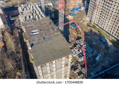 Aerial high top drone view. Pouring cement on the floors of residential multi-story building under construction using a concrete pump truck with high boom to supply the mixture to the upper floors