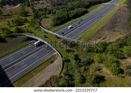 Aerial of highway traversed by wildlife crossing forming a safe natural corridor bridge for animals to migrate between conservancy areas. Environment nature reserve infrastructure eco passage.