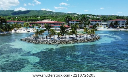An aerial of hotels on a beach covered with greenery against a turquoise sea in Montego Bay, Jamaica