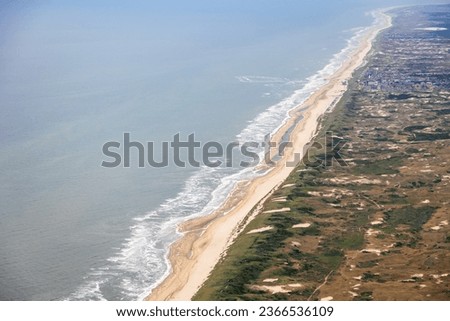 Aerial image of the Dutch coastline with breaking waves on the golden beach and sand dunes protecting The Netherlands 