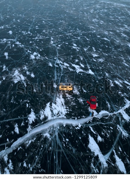 Aerial image of frozen Baikal lake in winter.\
Two cars standing on the frozen lake. Beautiful patterns on the\
ice. Abraham Lake, Lake\
Superior.