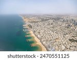 Aerial image of Israel city Tel Aviv with beach and downtown city seen from landing aircraft at Ben Gurion international airport. Many buildings and blue water.