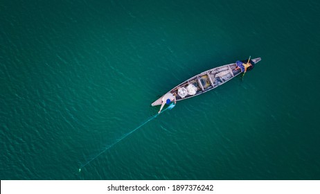 Aerial image of a small wooden boat in a lake and fishermen catching fish with a net. - Powered by Shutterstock