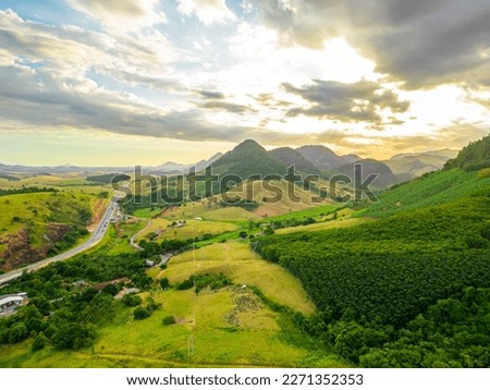 aerial image at sunset of the BR101 road passing through farms and villages in the interior of the state of Espírito Santo, Brazil.