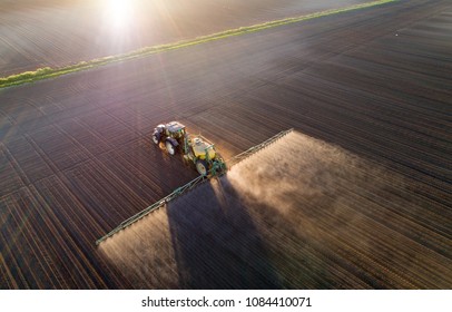 Aerial image of tractor spraying soil and young crop in springtime in field