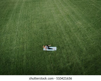 An aerial image of a woman doing yoga in a field of grass.