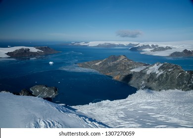 Aerial Images Of Mountains With Snow, Icy Sea And Icebergs In Antartica.