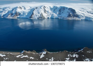 Aerial Images Of Mountains With Snow, Icy Sea And Icebergs In Antartica.