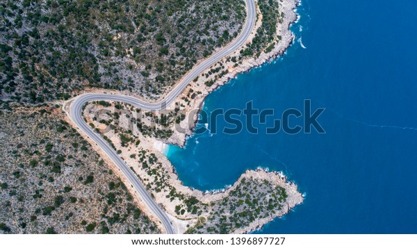 Aerial landscape of coastline and a road seascape. Car
drives down the empty asphalt road running along the sunny
Mediterranean shoreline of Turkey. Tourist car cruises down the
scenic coastal road .