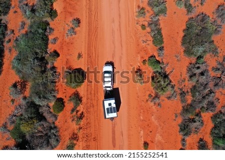 Aerial landscape drone view of 4WD vehicle towing an off road caravan driving on a sand dirt road during a road trip in Shark Bay Francois Peron National Park, Western Australia. No people. Copy space