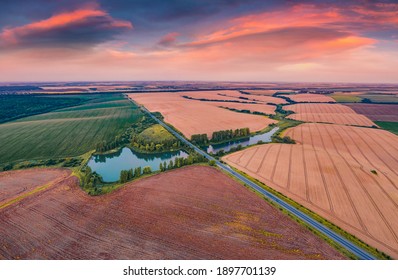 Aerial landscape photography. Spectacular summer sunset on the Ternopil outskirts with two lakes and asphalt road. Morning view of the Ukrainian countryside. Nice landscape of field of wheat.