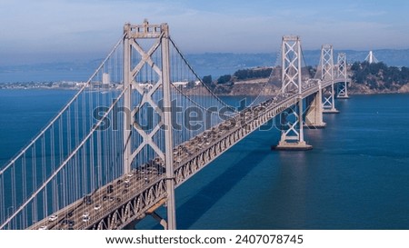aerial landscape view of area around San Francisco–Oakland Bay Bridge, a double-decked suspension spans - across San Francisco Bay - Car and Truck traffic driving on both decks on Interstate 80