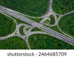 Aerial landscape view directly above a busy motorway junction cutting a swathe through dense woodland with green tree canopy providing carbon capture from exhaust fumes in an environmental concept