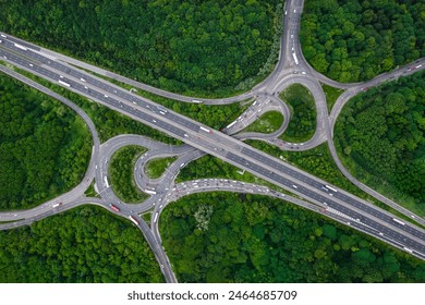 Aerial landscape view directly above a busy motorway junction cutting a swathe through dense woodland with green tree canopy providing carbon capture from exhaust fumes in an environmental concept - Powered by Shutterstock