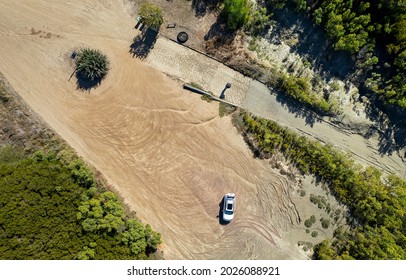 Aerial Landscape View Down Onto A Car Parked On Sand With Tyre Tracks Around It Beside A Boat Ramp. St Lawrence, Queensland, Australia