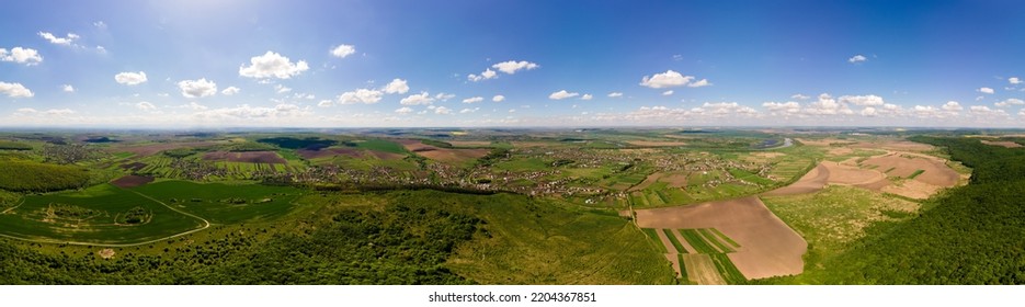 Aerial landscape view of green cultivated agricultural fields with growing crops and distant village houses - Shutterstock ID 2204367851
