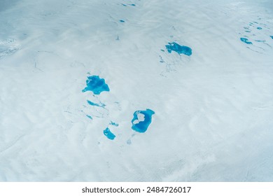 aerial landscape view of Greenland with snow covered surface and bright blue meltwater lakes in middle of icecap - The Arctic nature is UNESCO World Heritage - Powered by Shutterstock