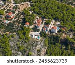 AERIAL: Luxury beachfront villas with swimming pools lay hidden in the fragrant pine forest of Hvar island. Flying above the touristic real estate properties of a scenic island in the Mediterranean.