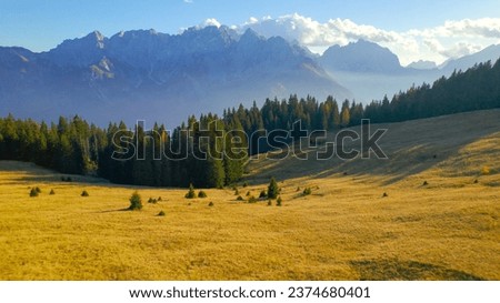 AERIAL: Majestic view of high mountaintops in Julian Alps on a sunny autumn day. Enchanting scenery in the Alpine world. Beautiful mountain range rising above forest and valley shrouded in gentle mist
