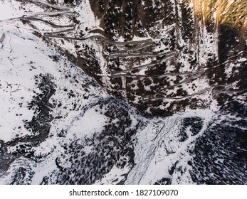 Aerial Majestic View Of Snowy Mountain Slope With Long Winding Road Going Through Snowy Mountainous Rocky Terrain In Serene Landscape