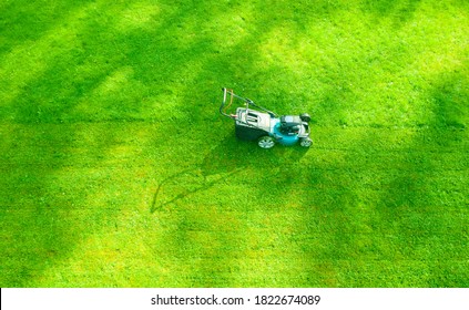 Aerial Mowing Lawns. Top Aerial View Lawn Mower On Green Grass. Mower Grass Equipment. Mowing Gardener Care Work Tool Close Up View. Sunny Day.