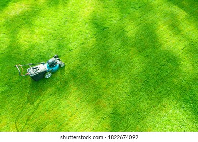 Aerial Mowing Lawns. Top Aerial View Lawn Mower On Green Grass. Mower Grass Equipment. Mowing Gardener Care Work Tool Close Up View. Sunny Day.