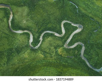 aerial nature landscape of winding river in green field, top view of beautiful texture from drone above