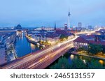 Aerial night skyline of Berlin, Germany, viewed from above Mill Dam Bridge over Spree River, with busy traffic on the streets, dazzling city lights and illuminated Television Tower in Alexander Square