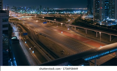 Aerial night view of empty highway and intersection in Dubai after epidemic lockdown. Cityscapes with disappearing traffic on streets. Roads and lanes crossroads without cars, Dubai, United Arab