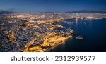 Aerial night view over the illuminated skyline of Piraeus, Athens, Greece, with Kstella Hill, Mikrolimano marina until the Faliro district