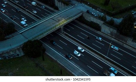 Aerial Night View Of An Overhead Road And Bridge Crossing An Italian Highway. On The Road, Many Cars Drive At High Speed With The Headlights On.