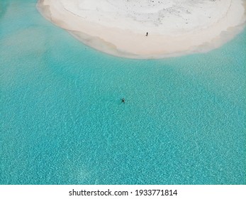 Aerial of one man floating in Indian Ocean on lonely Maldivian beach. Drone shot of turquoise water and sandbank. Isolation and vacation of couples honeymoon. Picturesque tropical destination.  - Powered by Shutterstock