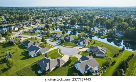 Aerial over culdesac with suburban houses in neighborhood with manmade river between homes