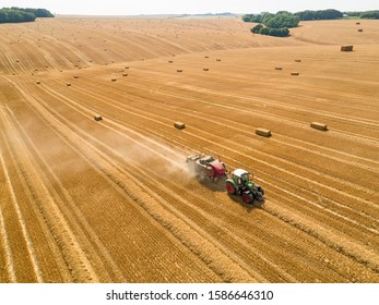 Aerial Overhead Of Tractor Baler Straw Bales In Field After Wheat Harvest In Summer On Farm