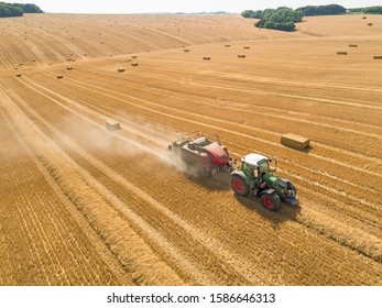 Aerial Overhead Of Tractor Baler Straw Bales In Field After Wheat Harvest In Summer On Farm