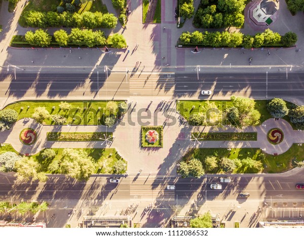 aerial overhead view of main street in the city\
with traffic and green\
trees