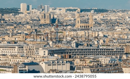 Aerial panorama above houses rooftops in a Paris timelapse. Evening view of Notre Dame de Paris and Saint-Sulpice before sunset. Cranes on a construction site
