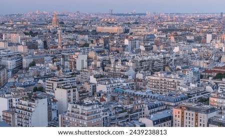 Aerial panorama above houses rooftops in a Paris day to night transition timelapse. Evening view with les invalides dome and other sightseeings illuminated after sunset