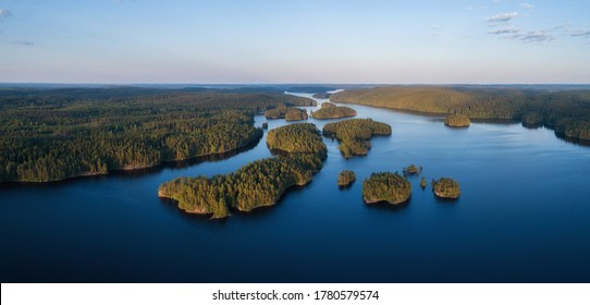 Aerial panorama of beautiful blue lake, islands and green summer forest in Finland. Blue sky. Top view. Summer sunset lanscape.