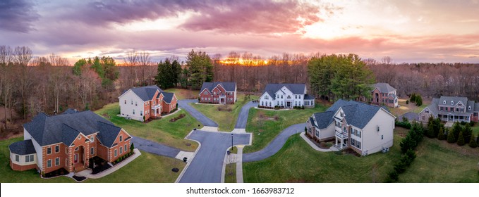 Aerial Panorama Of Brick Facade Luxury Mansion Type Single Family Homes Neighborhood Cul-de-sac Street American Real Estate New Construction In Maryland USA With Dramatic Colorful Sunset Sky