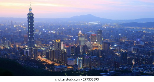Aerial panorama of busy Taipei City at dusk, with a view of Taipei 101 Tower in downtown area and Tamsui River and distant mountains in the background ~ A Blue and Gloomy evening scenery of Taipei