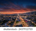 Aerial panorama of city of West Hollywood art dusk. Los Angeles, California. A vibrant sunset blankets the sky with shades of pink and orange, casting a warm glow over a bustling cityscape panorama.